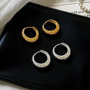 Close-up detail of textured hoop earrings in gold and silver finish for luxury style.