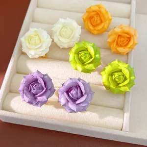 Close-up of colorful rose flower stud earrings displayed in a velvet jewelry tray