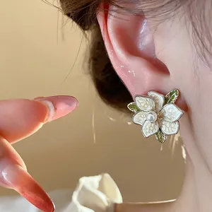 Elegant French style enamel flower stud earrings with pearl center shown on ear model