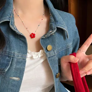 Close-up of a vibrant red flower beaded necklace worn by a model in denim jacket