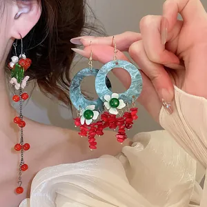 Detailed view of vintage Chinese style tassel earrings with blue hoops and red stones.