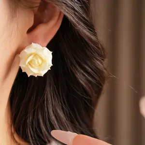 Close-up macro detail of cream rose flower stud earrings with elegant petal textures