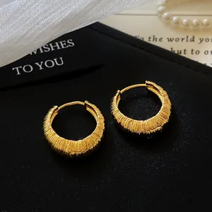 Close-up of elegant gold textured hoop earrings with a vertical ribbed pattern design.