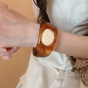 Detailed shot of a wide amber marbled resin bangle with a cream-colored oil-drop center.