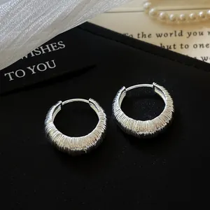 Macro detail view of silver textured hoop earrings with minimalist ribbed pattern.