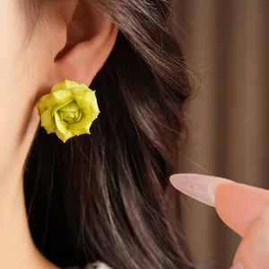 Detailed macro view of a green flower stud earring with 18K gold plating on model's ear
