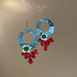 Detail showing the blue circular disc and red stone tassels of these vintage earrings.