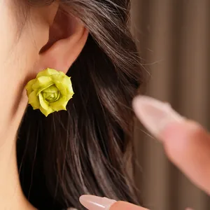 Close-up of lime green rose stud earrings on ear for a delicate floral look