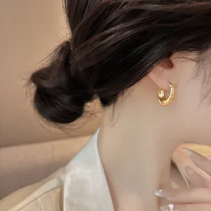 Close-up detail of a golden textured hoop earring worn by a model in a luxury style