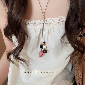 Close-up of a Zen-style acorn pendant necklace with wooden beads worn by a model
