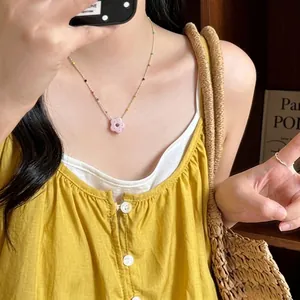 Detailed shot of a colorful beaded necklace with a pink resin flower pendant.