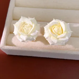 Close-up detail of elegant white rose stud earrings displayed on jewelry tray
