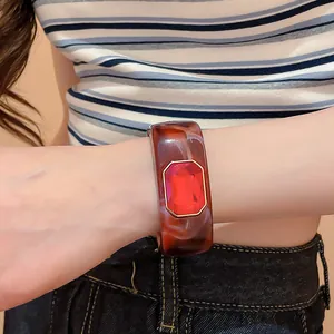 Close-up detail of a vintage resin bangle with a large faceted red gemstone inlay