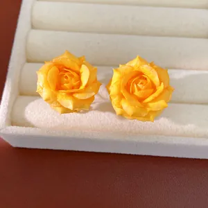 Close-up of elegant yellow rose flower stud earrings in white jewelry tray display