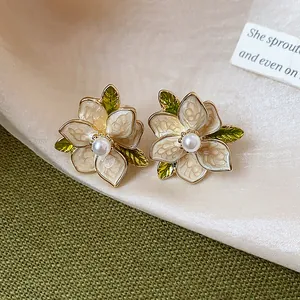 Close-up detail of elegant French style floral stud earrings with white enamel and pearl