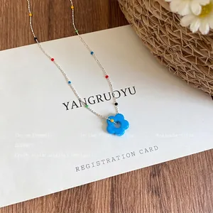 Macro shot of a vibrant blue flower pendant necklace with colorful accent beads