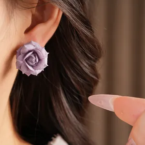 Macro view of a purple rose stud earring worn on an ear