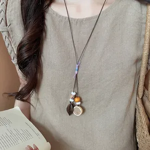 Close-up of a Zen-style acorn pendant necklace with wooden beads and woven details.