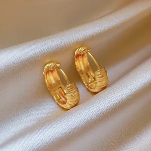 Exquisite close-up of textured gold hoop earrings on elegant silky white fabric background
