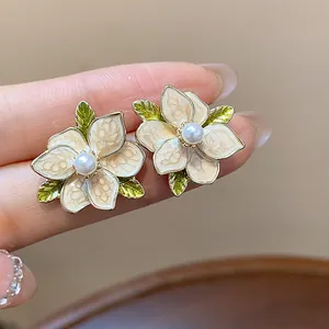Macro detail view of elegant French style enamel flower stud earrings featuring white pearl centers