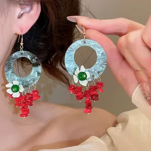 Close-up of retro neo-Chinese geometric earrings with floral and red bead tassels