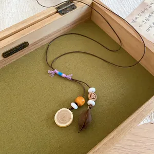 Close-up of a Zen-style acorn pendant necklace with a wood slice and beads displayed in a wooden box