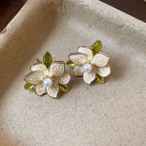 Detailed close-up of French style enamel floral earrings with central white pearls.