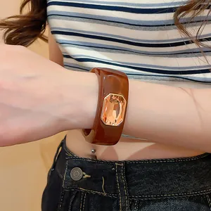 Close-up of a chunky amber resin bracelet with a large orange crystal on model