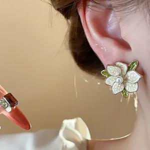 Close-up of elegant French floral enamel stud earrings with pearl center worn on ear