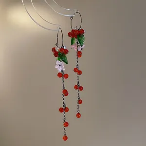 Macro view of vintage Chinese style tassel earrings with red berries and green leaves