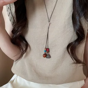 Macro view of a Zen-style woven necklace with a dark brown acorn pendant and beads