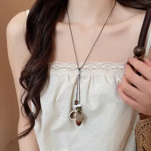 Close-up detail of a vintage acorn pendant necklace worn over a cream lace top garment