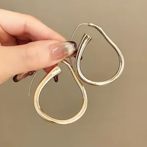 Primo piano dettagliato di orecchini a cerchio dorati irregolari dal design minimalista