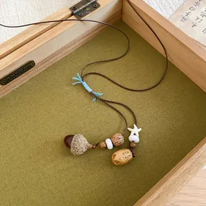 Detailed close-up of handmade acorn pendant necklace with wooden beads in box