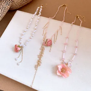 Detailed view of three elegant pink floral necklaces with pearl and crystal beads jewelry