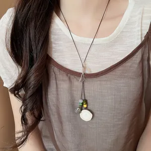 Detailed close-up of a New Chinese style acorn pendant necklace with colorful beads on a model