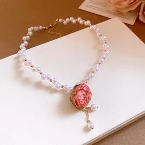 Detailed view of sweet pink rose pendant and pearl beaded necklace with gold accents