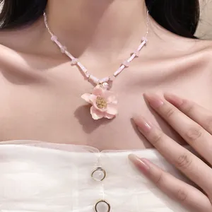 Detailed close-up view of a sweet pink rose flower pendant on a delicate beaded necklace