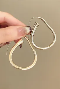 Primo piano di orecchini a cerchio dorati irregolari a forma di pera con finitura lucida