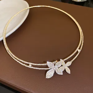 Dettaglio del girocollo dorato a doppio strato con pendente a fiore in strass scintillanti.