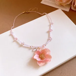 Detail shot of a romantic pink rose flower pendant necklace with bead chain.