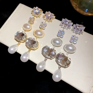 Detailed view of square and oval rhinestone tassel earrings with faux pearls in gold and silver