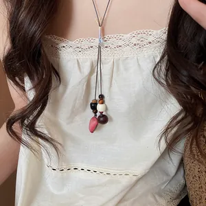Close-up of a vintage Chinese style acorn pendant necklace worn on a white lace top.