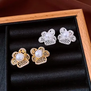 Détail de boucles d'oreilles fleurs ajourées avec perles en or et argent