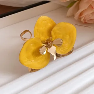 Primo piano di orecchini a lobo a forma di fiore giallo con dettagli dorati.