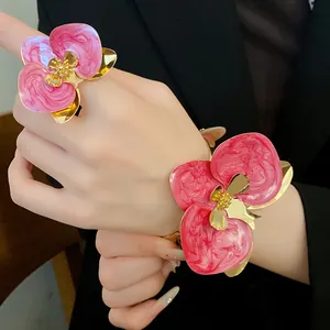 Dettaglio ravvicinato di anello e bracciale vintage a fiore in smalto rosa e oro