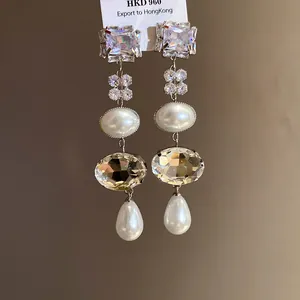 Detail showing elegant long tassel earrings with square crystals and white teardrop pearls.