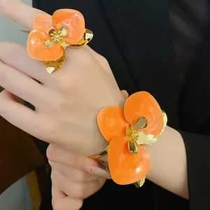Dettaglio di set con anello e bracciale a polsino con grandi fiori in smalto arancione