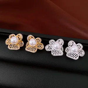 Gros plan de boucles d'oreilles fleurs avec perles et zircons ajourés en or et argent