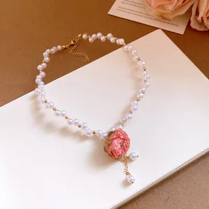 Exquisite detail shot of a handmade pink rose flower pendant on a white pearl necklace